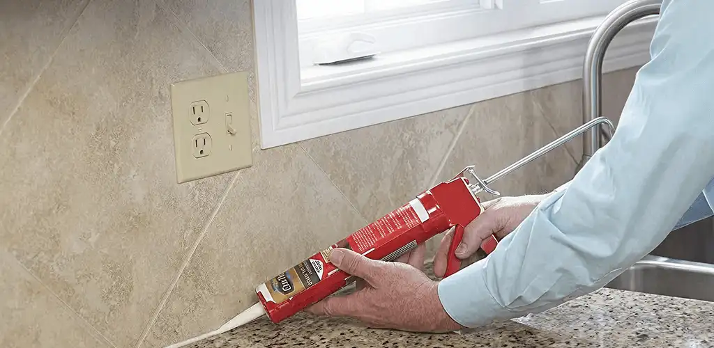 Handyman applying caulk along a kitchen backsplash and countertop seam in Cape Coral, FL